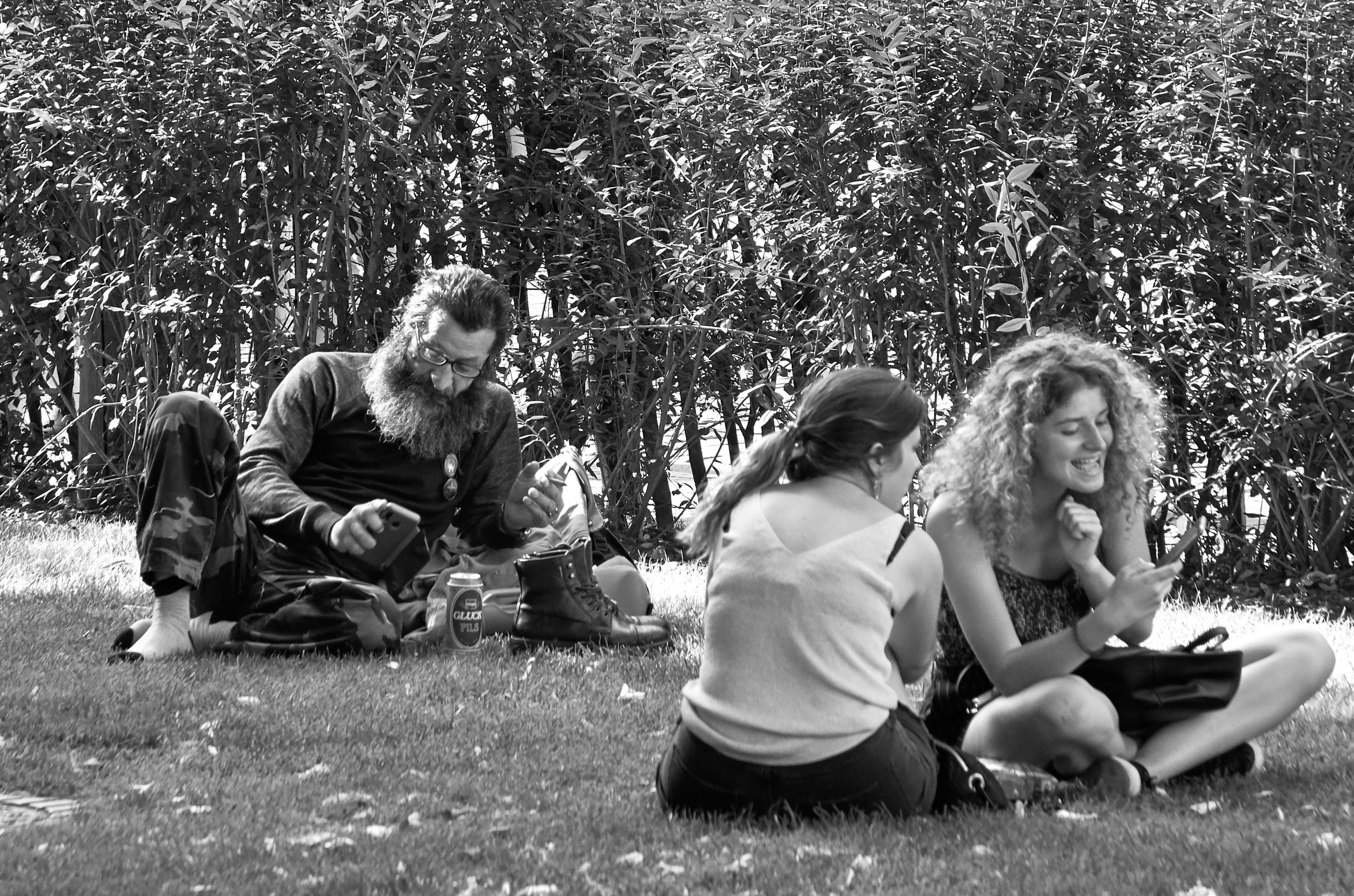 Photo noir et blanc d'un homme et deux femmes assises dans l'herbe dans un parc