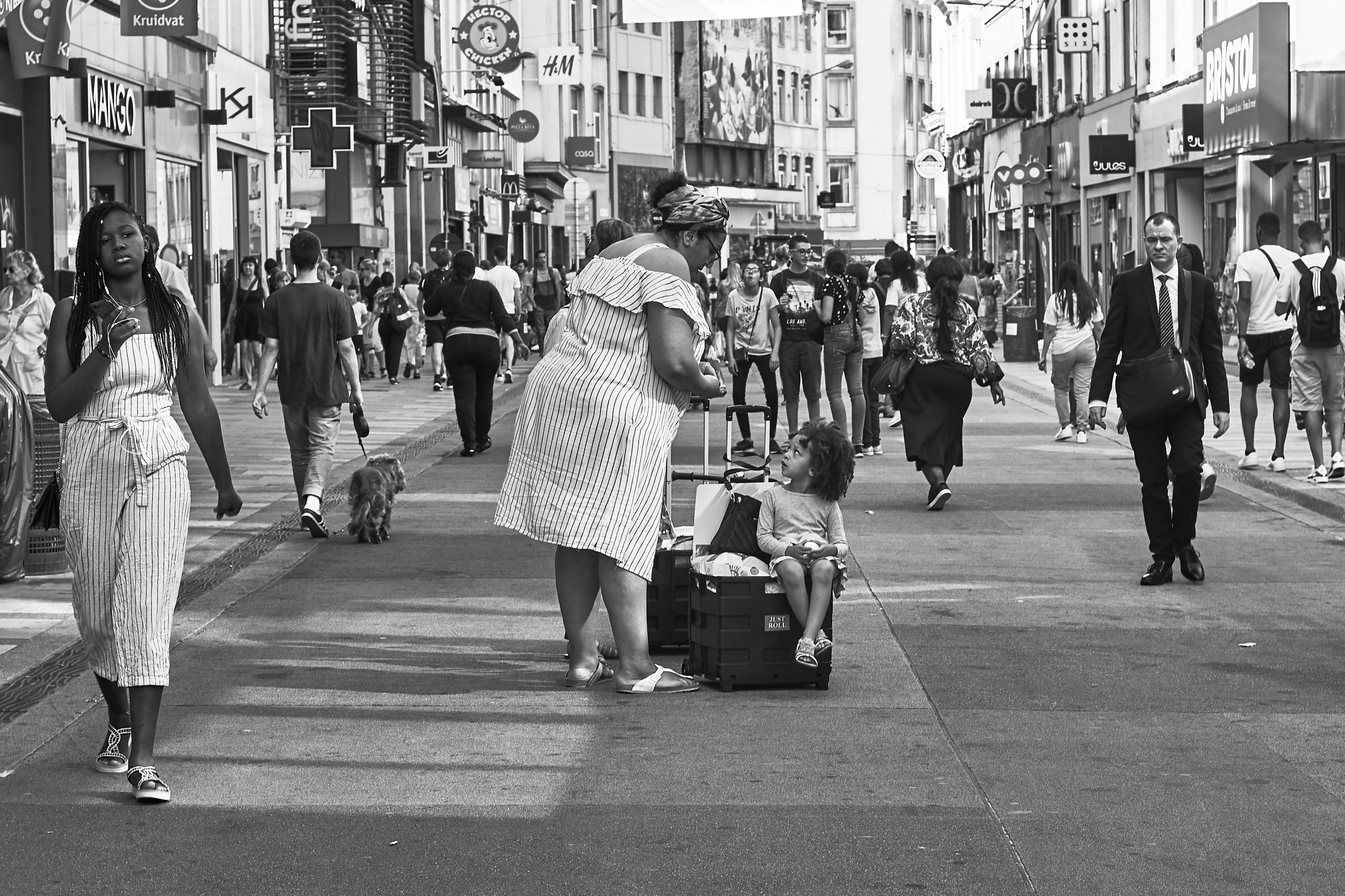 Photo noir et blanc d'une rue dans le centre ville de Bruxelles avec une maman et son enfant ayant fait des courses