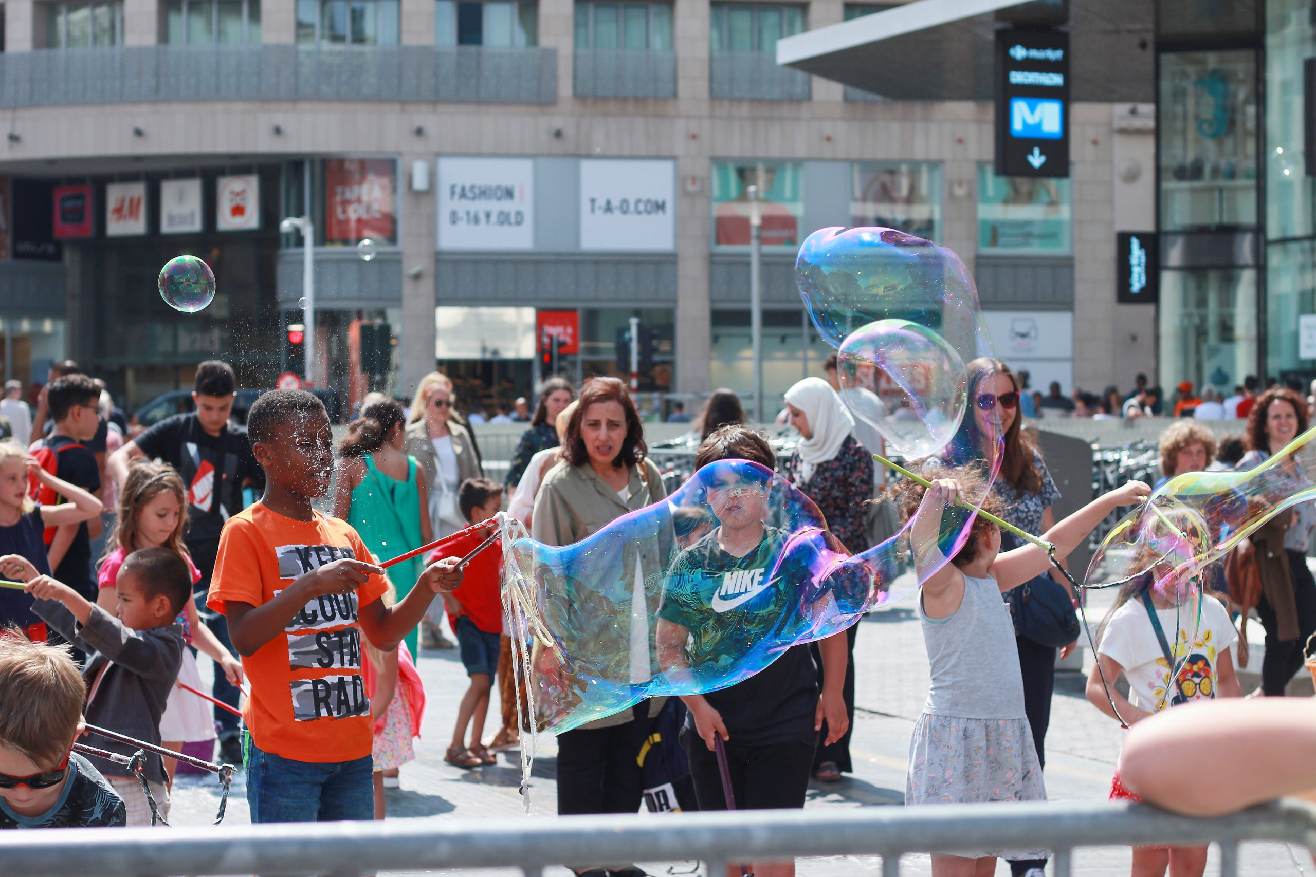 Enfants dans le centre ville de Bruxelles réalisant des bulles de savon XXL